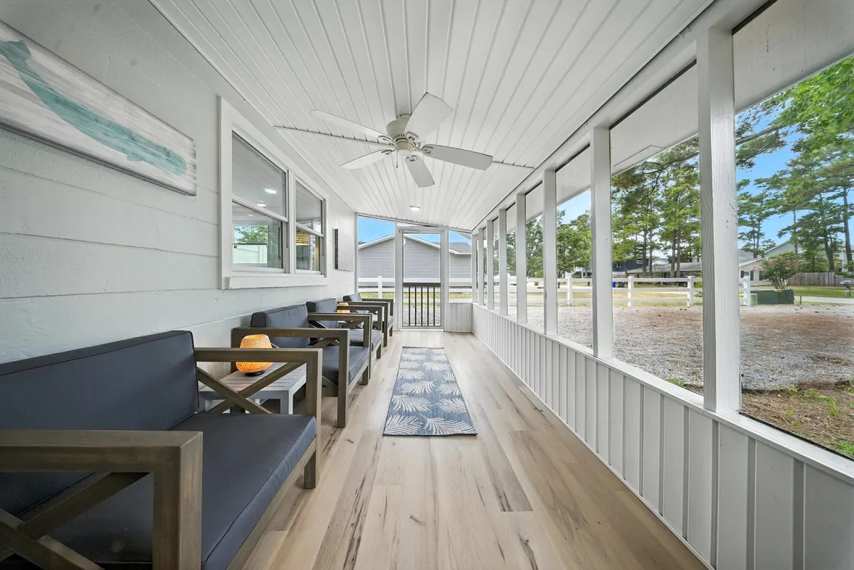 Long screened porch with shiplap ceiling, ceiling fan and outdoor seating at a Charlotte home, photographed by Luma Real Estate Media