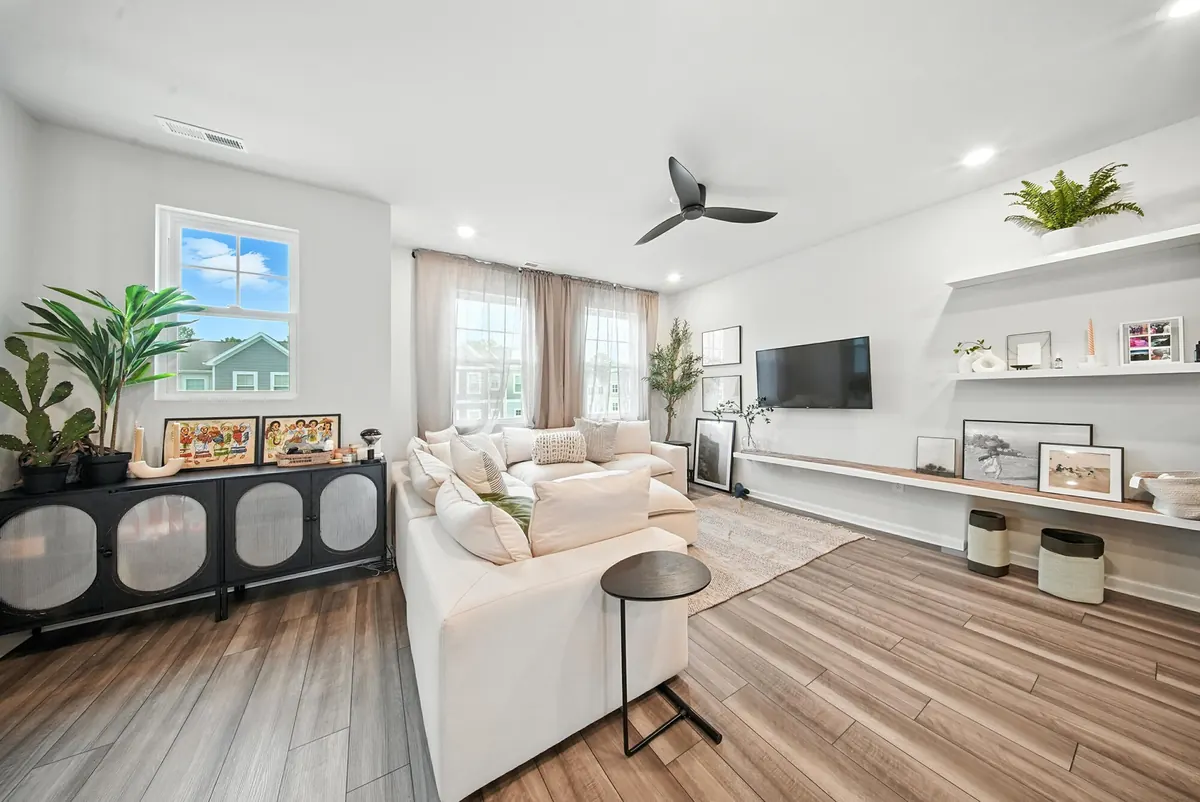 Airy Charlotte townhome living room with white sofa, built-in shelving and large windows, photographed by Luma Real Estate Media