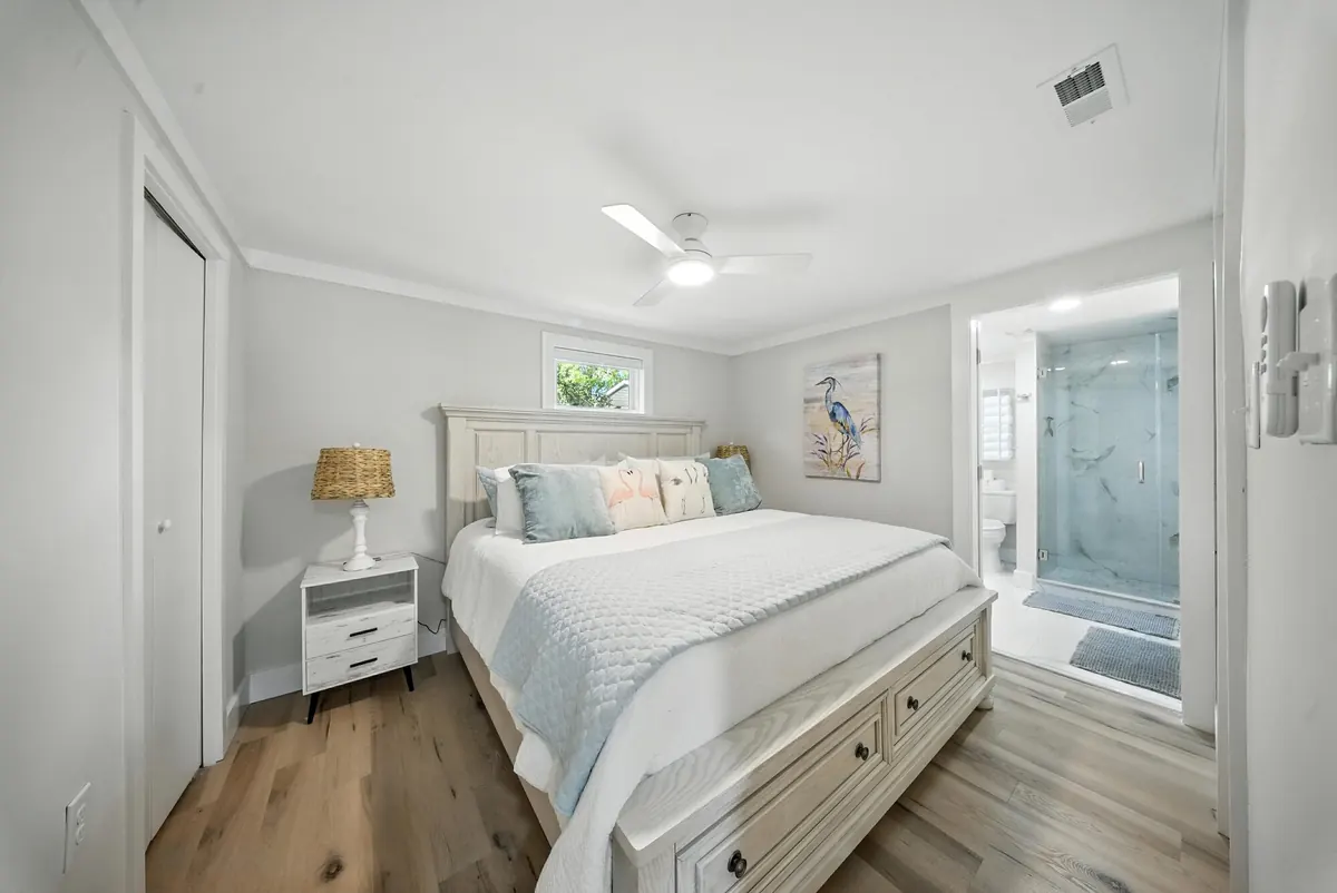 Coastal-style bedroom with a white bed and view into the en-suite bath in a Lake Norman listing, photographed by Luma Real Estate Media