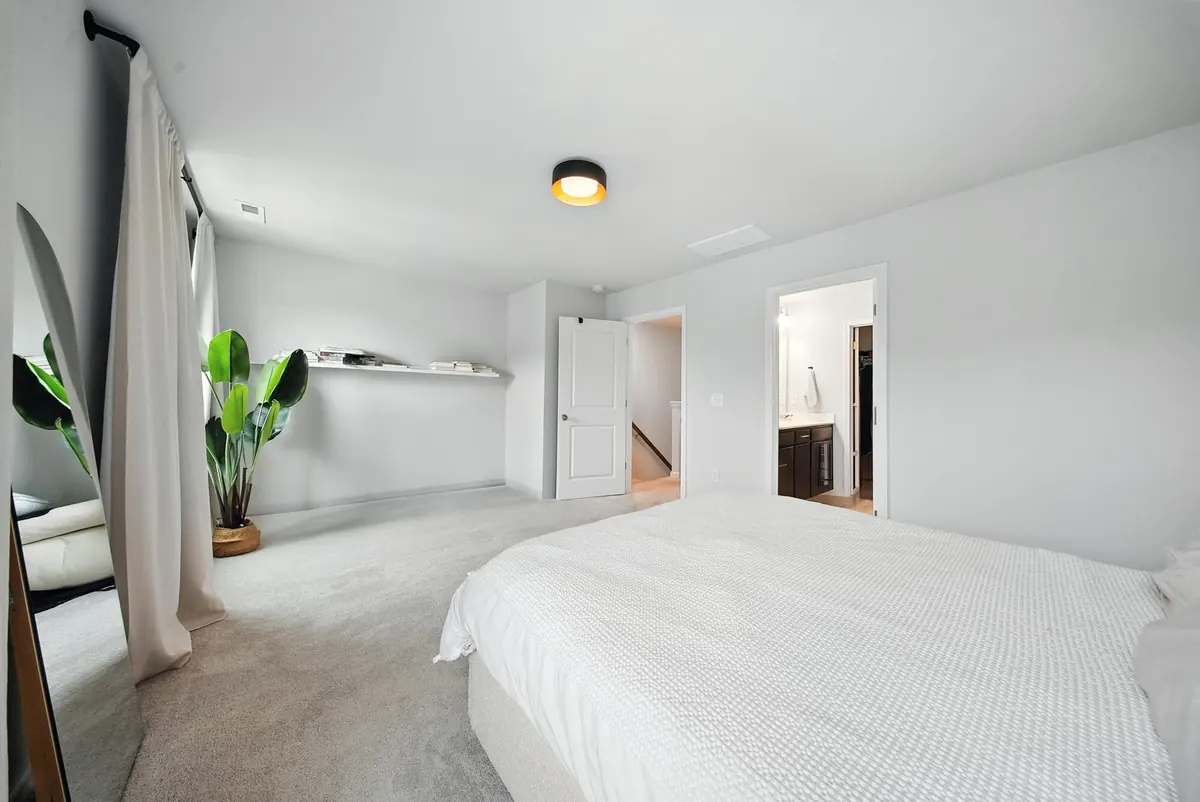 Spacious primary bedroom with crisp white bedding, natural light and indoor plants, HDR photographed by Luma Real Estate Media